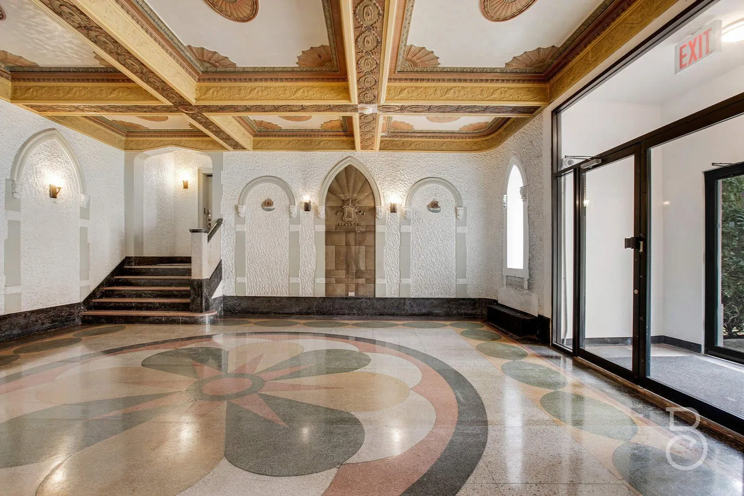 a big room with wooden floor a chandelier fan and windows
