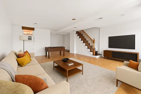 a view of an empty room with wooden floor and stairs