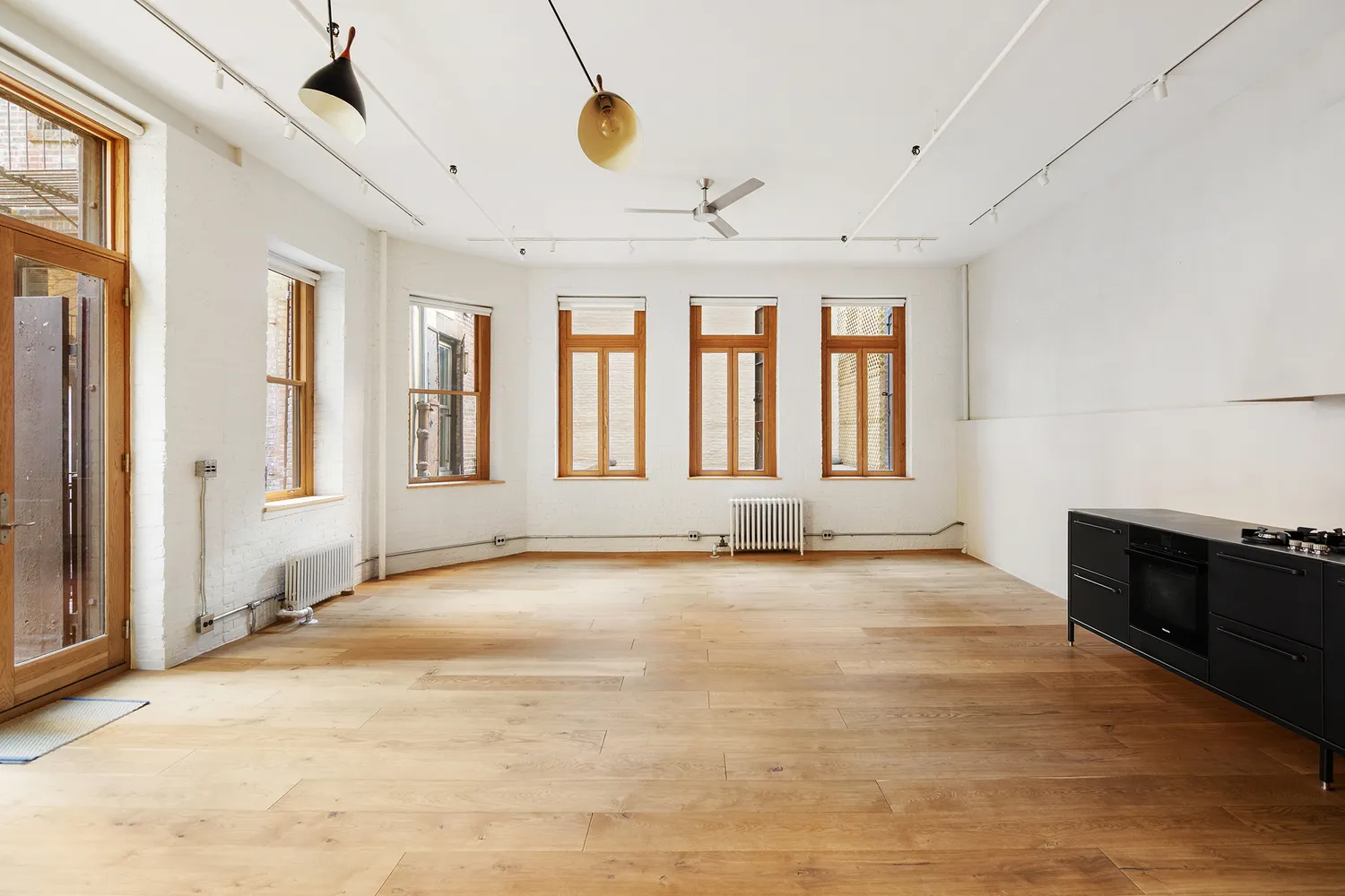 a view of an empty room with a window and a kitchen