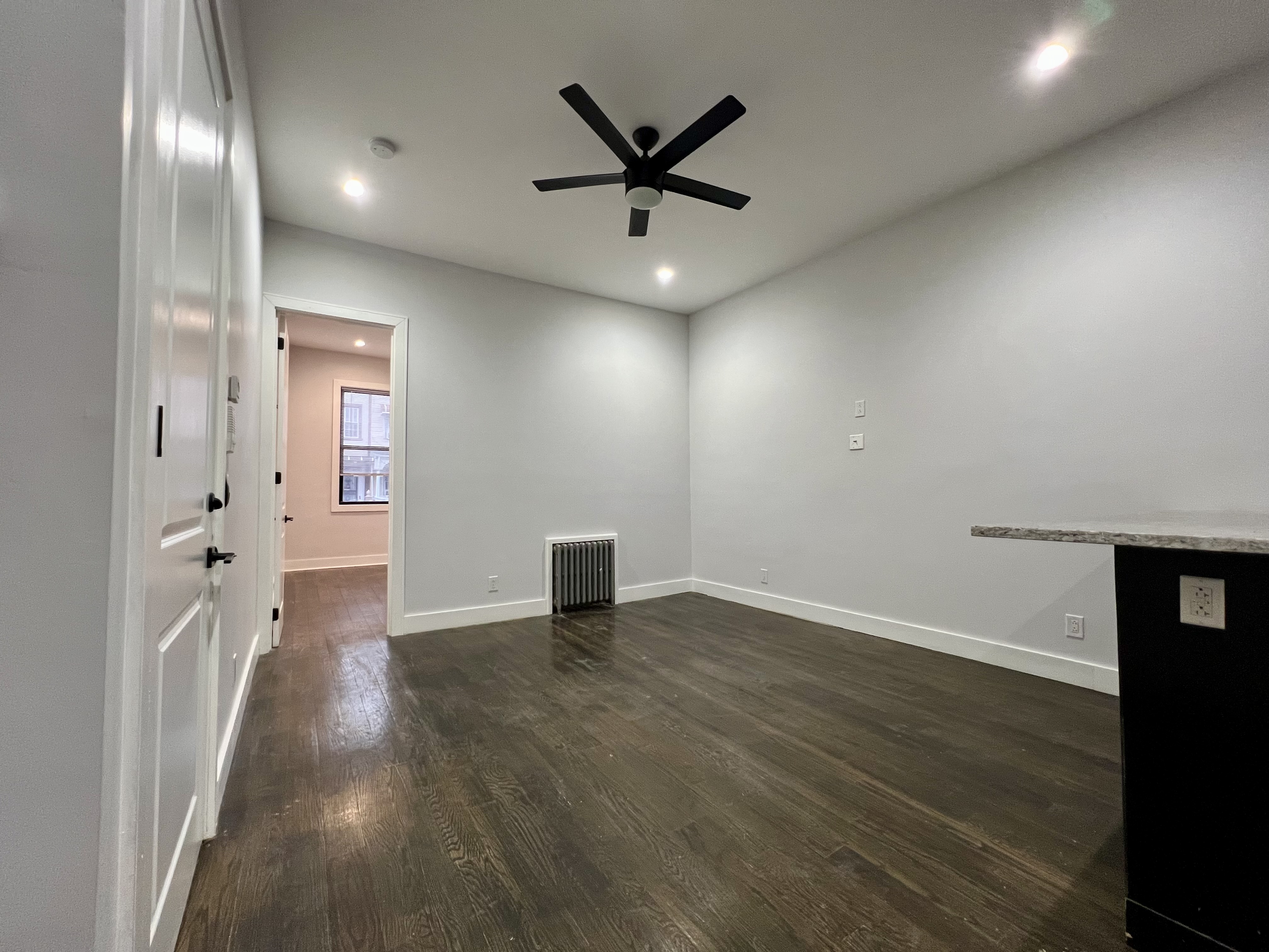 20 Suydam Street, Unit 1 Brooklyn, NY 11221 - Photo 4 of 10 an empty room with wooden floor and a ceiling fan