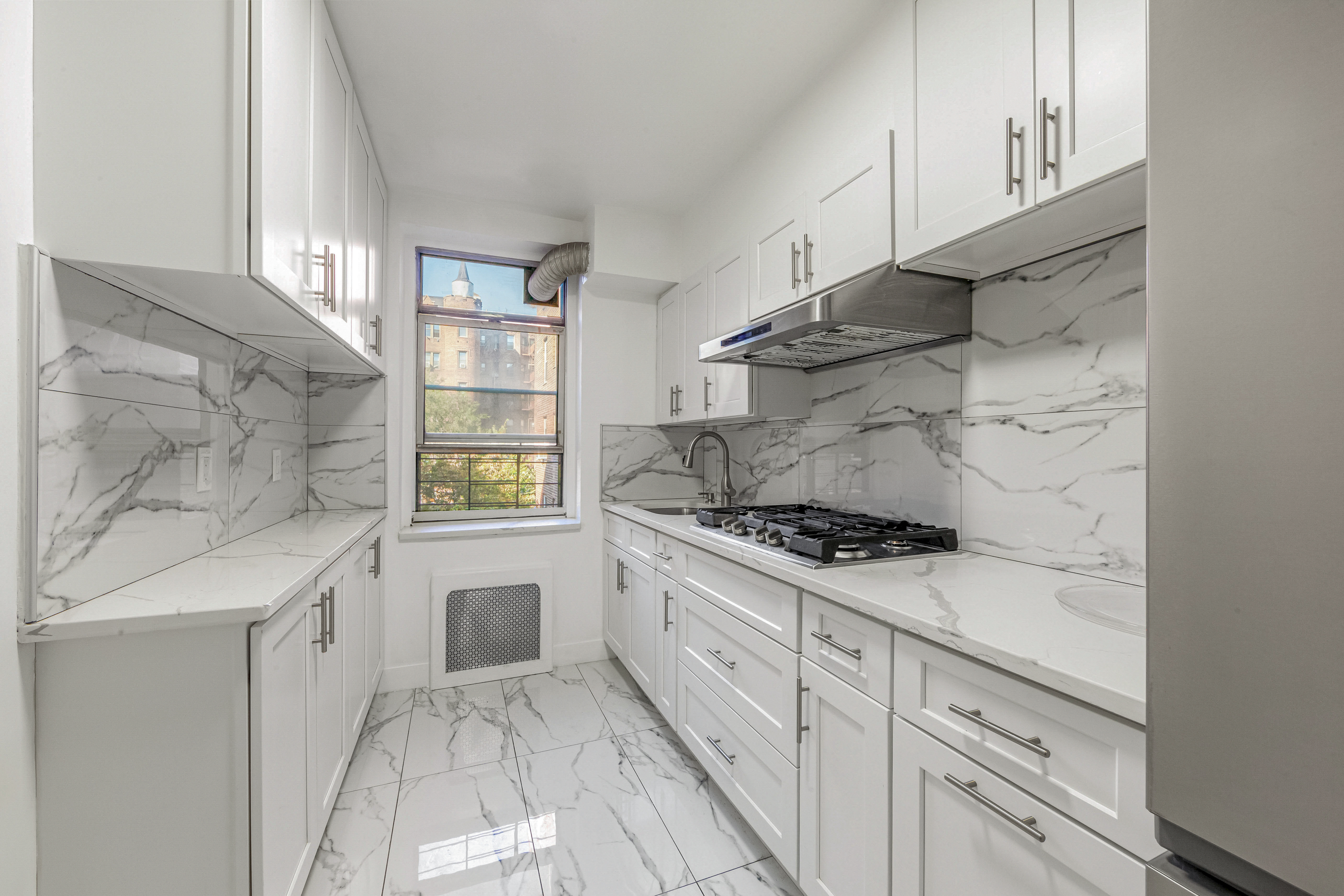 76-10 34th Avenue, Unit 2H Queens, NY 11372 - Photo 5 of 12 a kitchen with white cabinets and appliances