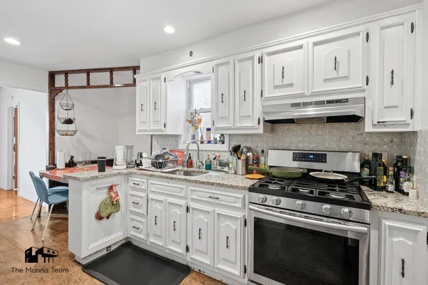 a kitchen with stainless steel appliances granite countertop a stove and white cabinets