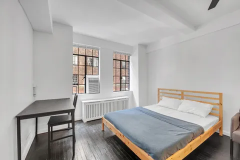 a bedroom with a bed a table and windows