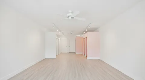 a view of a room with wooden floor and a ceiling fan