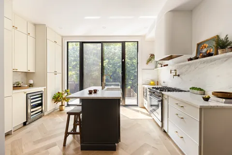 a kitchen with a stove a sink and white cabinets with wooden floor