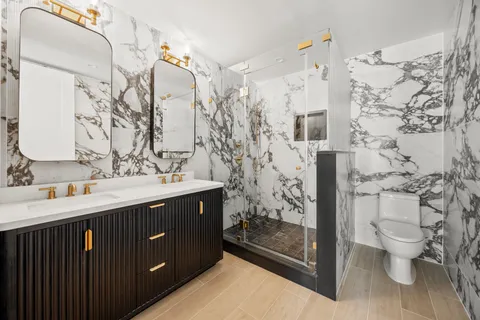 a bathroom with a double vanity sink toilet and shower