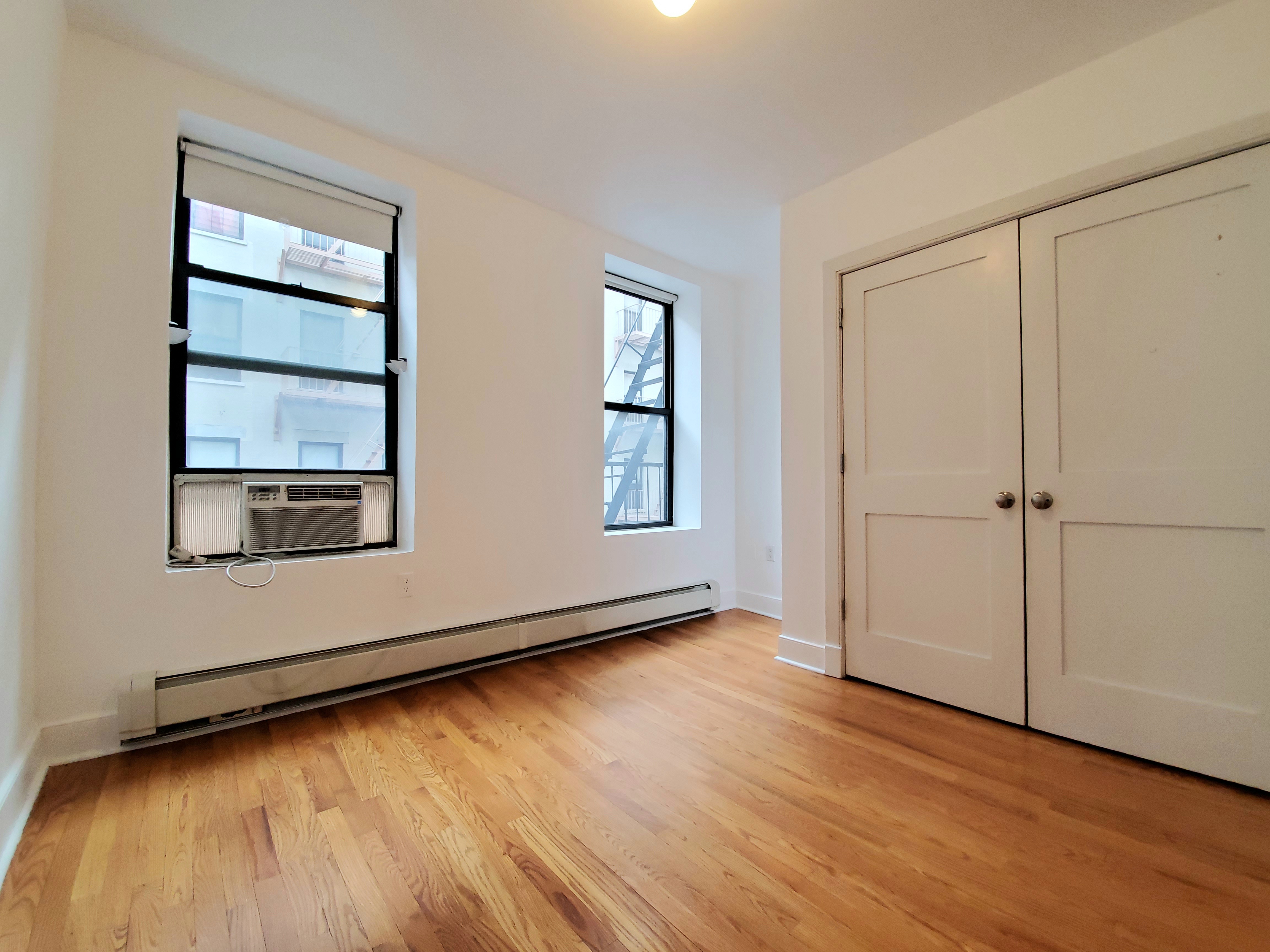 305 West 150th Street, Unit 307 Manhattan, NY 10039 - Photo 5 of 7 an empty room with wooden floor and windows