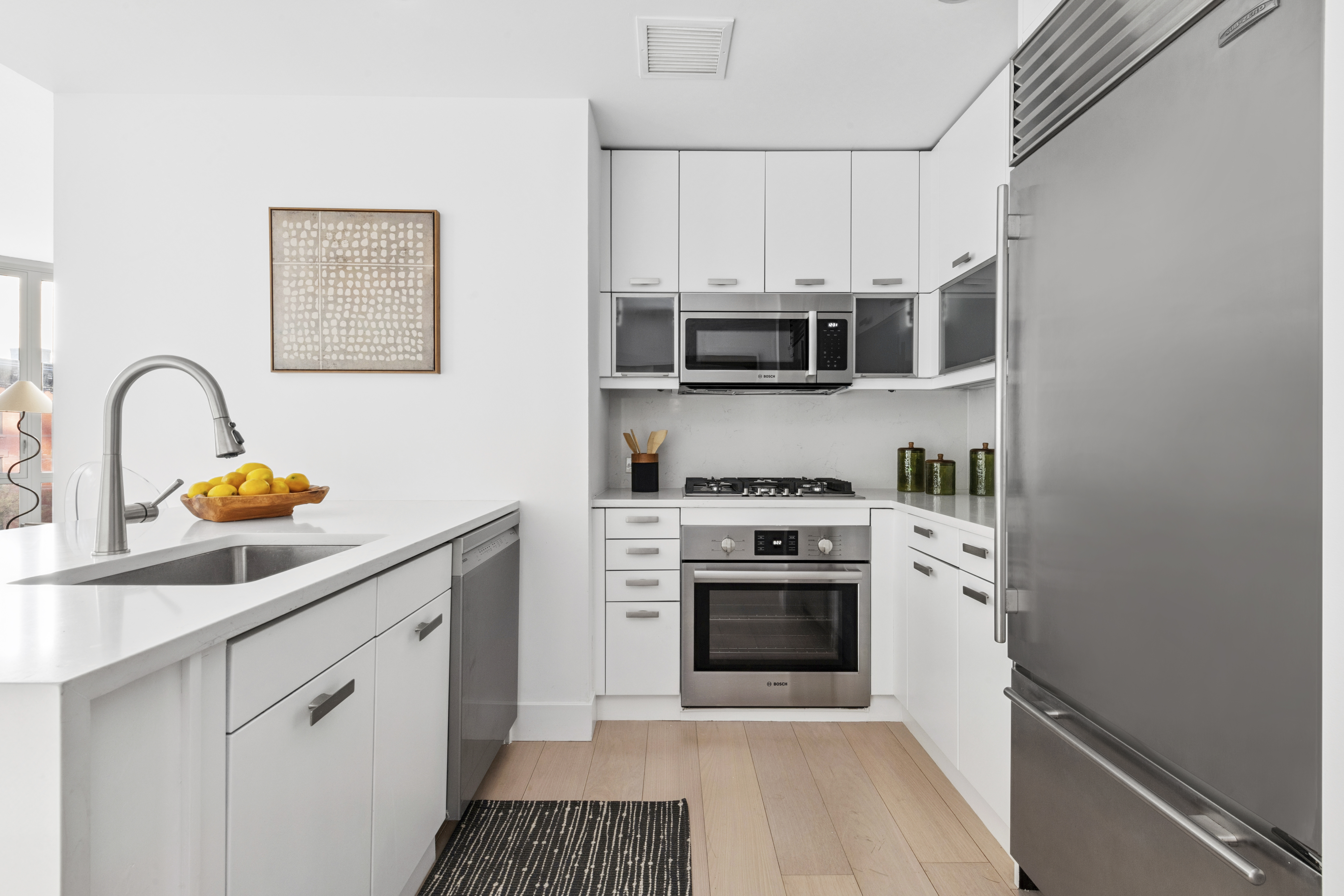 225 East 34th Street, Unit 5E Manhattan, NY 10016 - Photo 4 of 23 a kitchen with stainless steel appliances granite countertop a stove a microwave and a sink