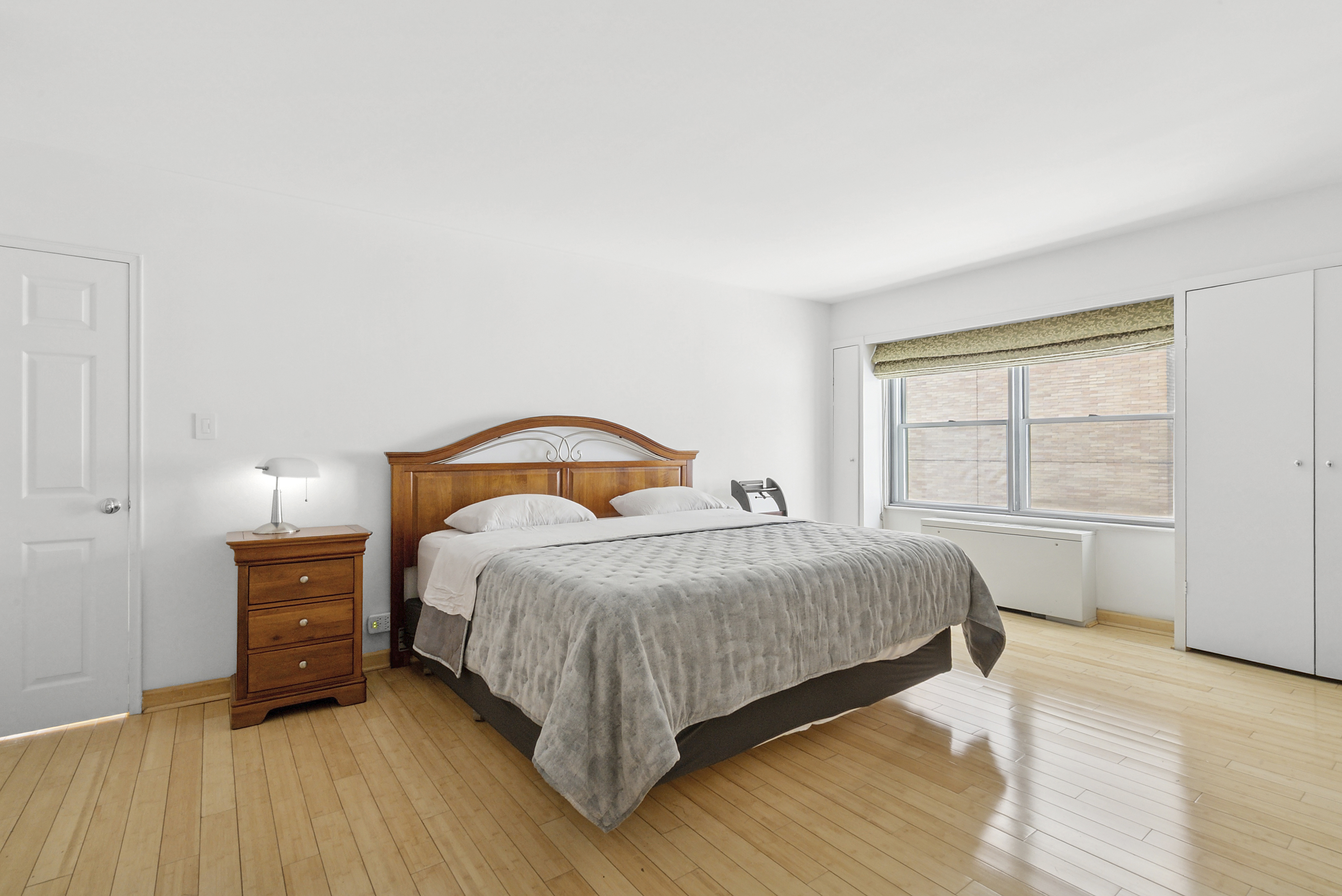 118 East 60th Street, Unit 4H Manhattan, NY 10022 - Photo 5 of 10 a bedroom with a bed a window and dresser