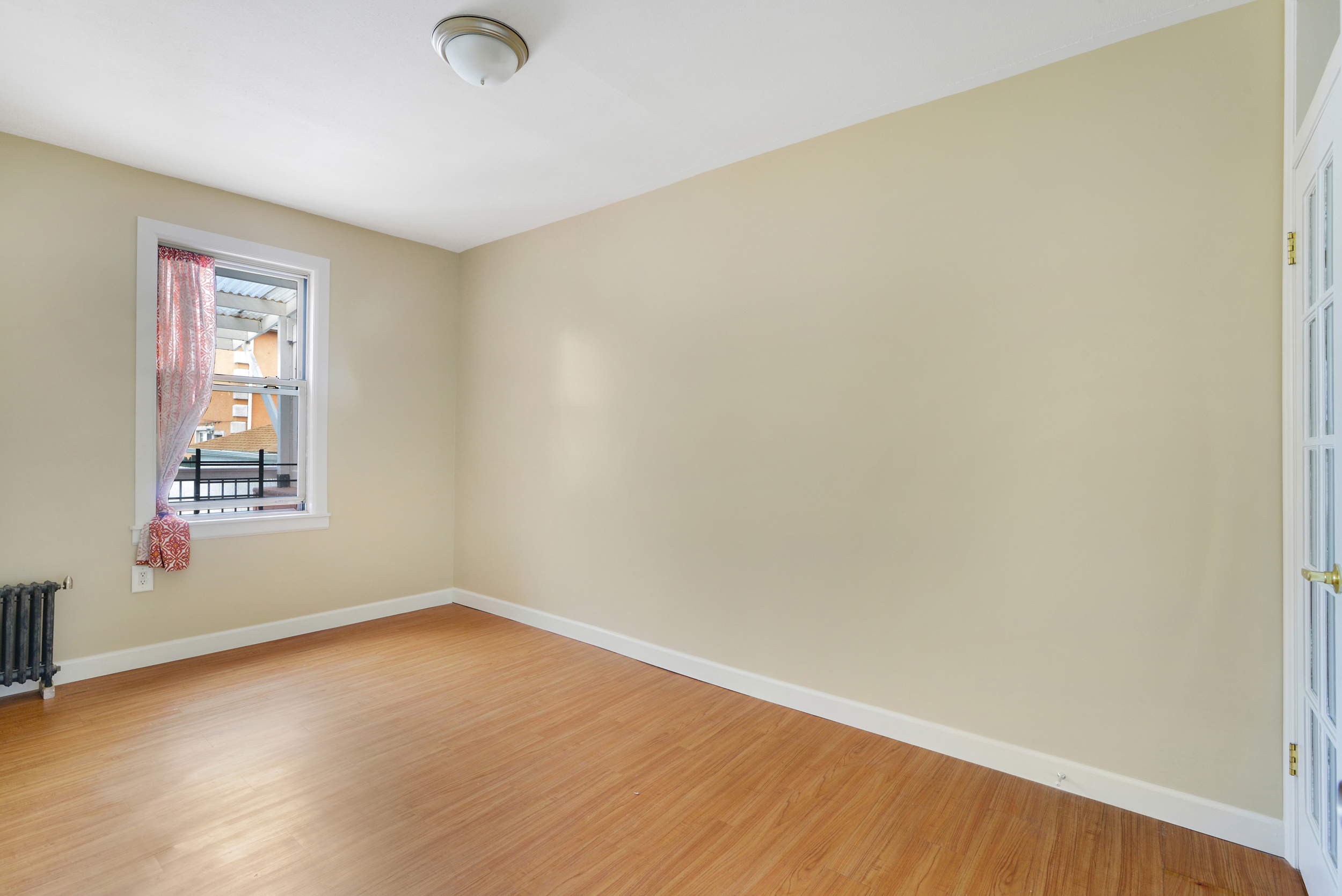 91-11 32nd Avenue, Unit 2 Queens, NY 11369 - Photo 5 of 9 an empty room with a window