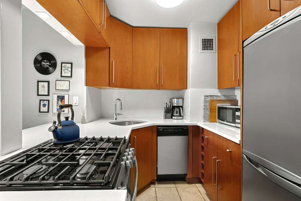 301 East 79th Street, Unit 17F Manhattan, NY 10075 - Photo 7 of 15 a kitchen with stainless steel appliances granite countertop a stove and a refrigerator