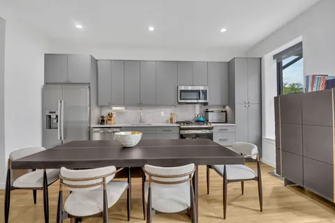 a kitchen with a dining table chairs and refrigerator
