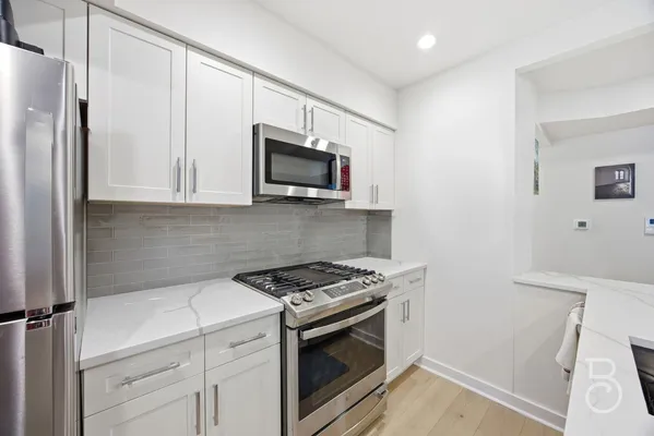 a kitchen with stainless steel appliances white cabinets and a stove top oven