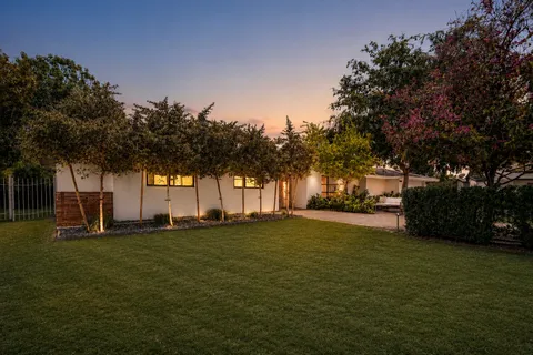 a big yard with large trees and a wooden fence