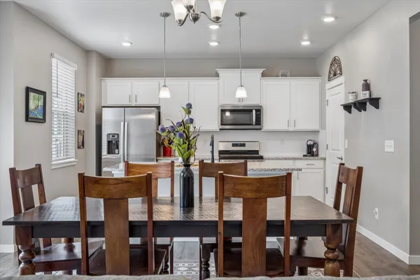 a dining room with stainless steel appliances kitchen island granite countertop a dining table chairs and a refrigerator