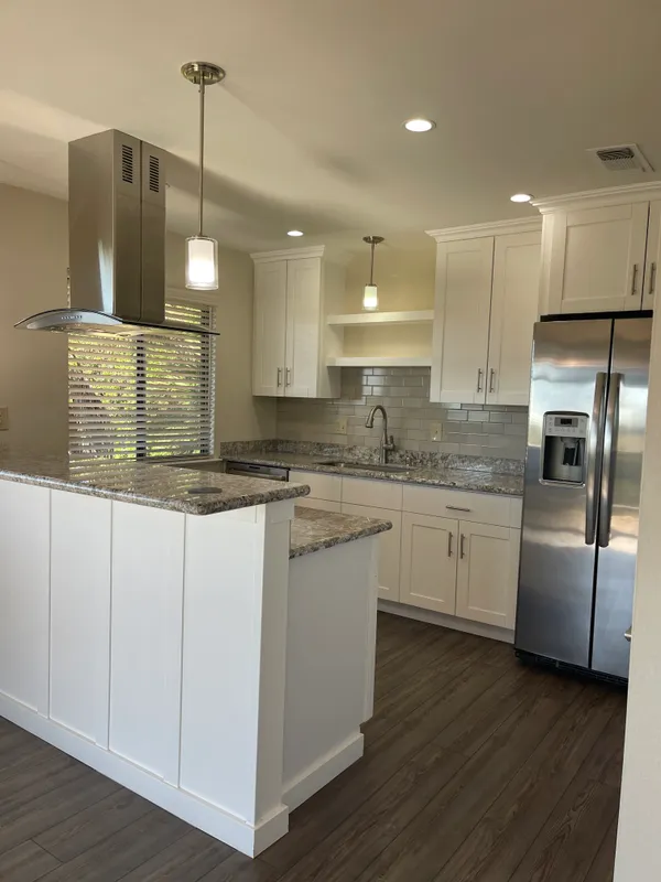 a kitchen with stainless steel appliances granite countertop a refrigerator a sink dishwasher a stove and white cabinets with wooden floor