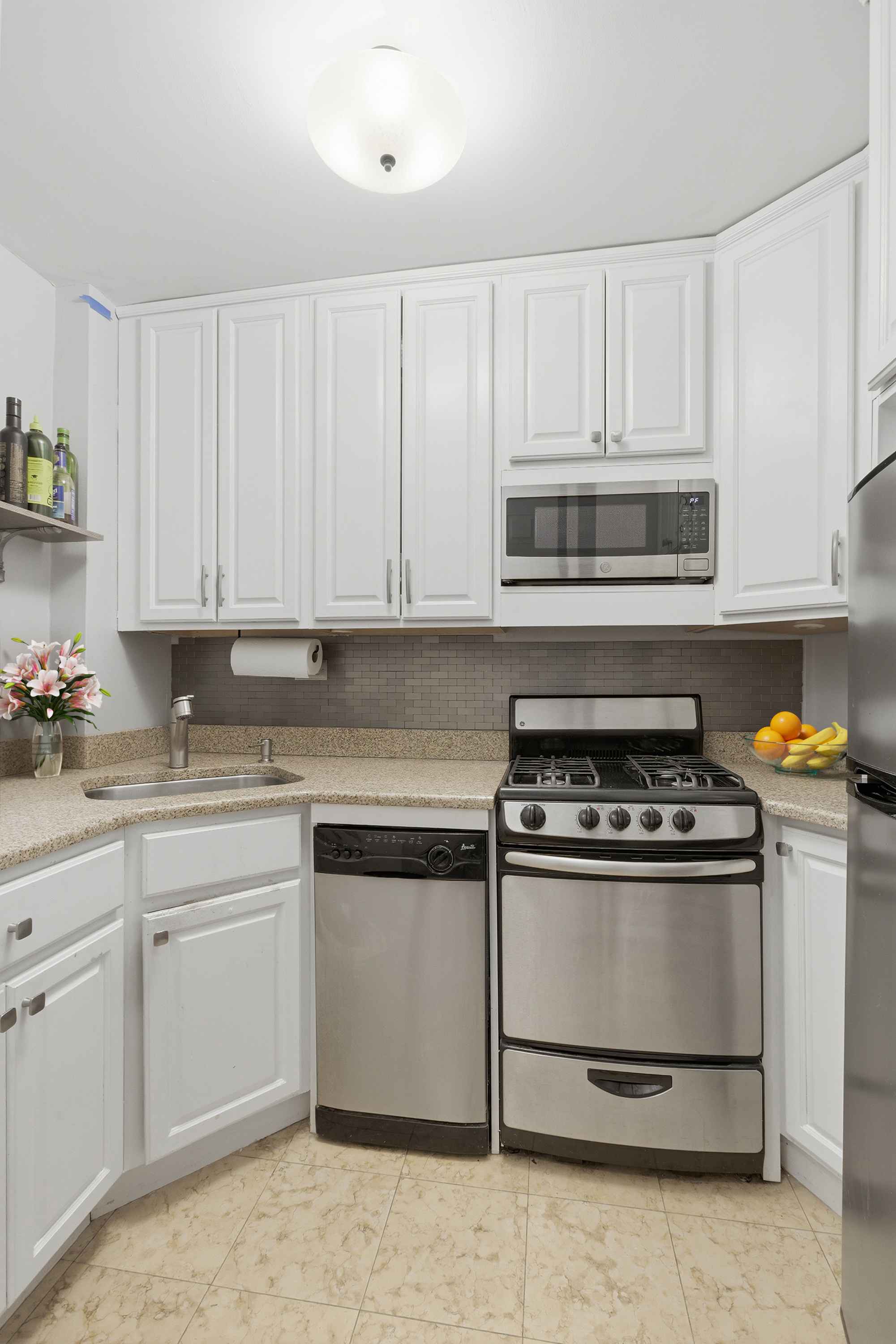 345 East 81st Street, Unit 12G Manhattan, NY 10028 - Photo 6 of 8 a kitchen with white cabinets stainless steel appliances and sink