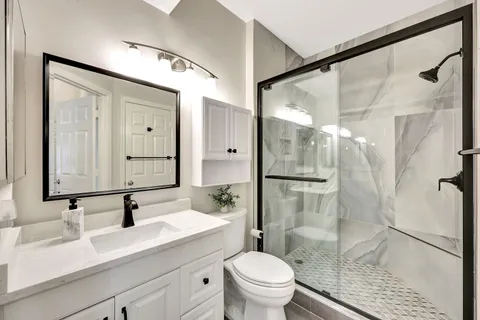 a bathroom with a sink vanity granite toilet and shower