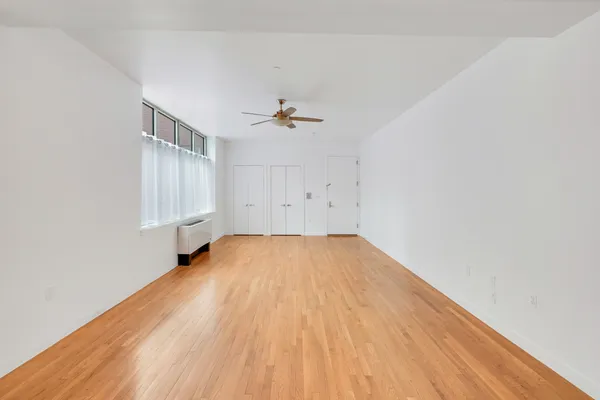 an empty room with a hardwood and a ceiling fan