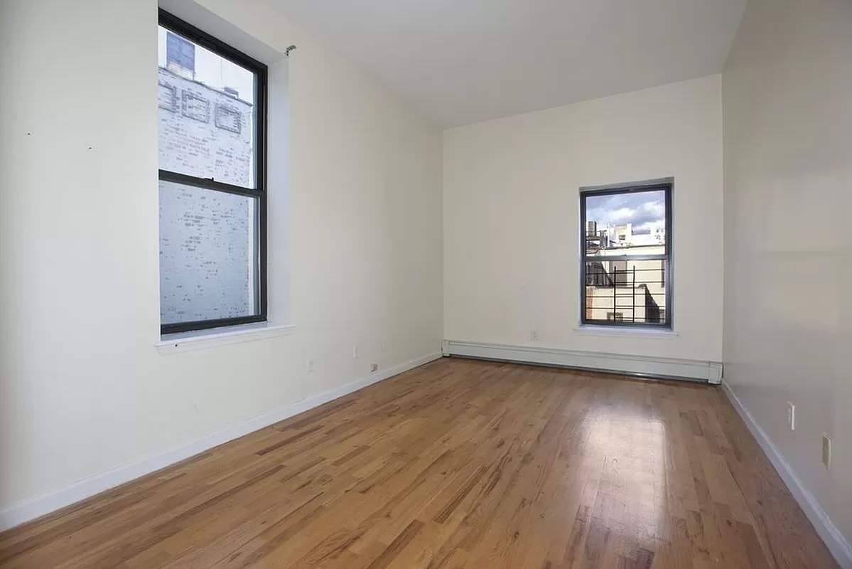 469 West 141st Street Manhattan, NY 10031 - Photo 8 of 14 an empty room with wooden floor and windows