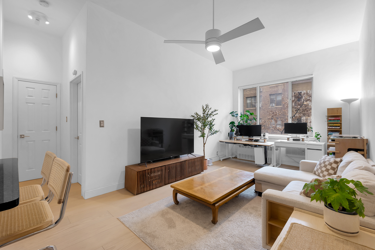 244 East 60th Street, Unit 3B Manhattan, NY 10022 - Photo 1 of 6 a living room with furniture a flat screen tv and a large window