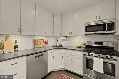 a kitchen with stainless steel appliances granite countertop grey cabinets a stove a sink and dishwasher