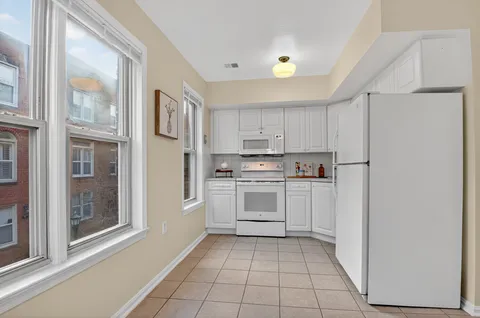 a kitchen with white cabinets and white appliances