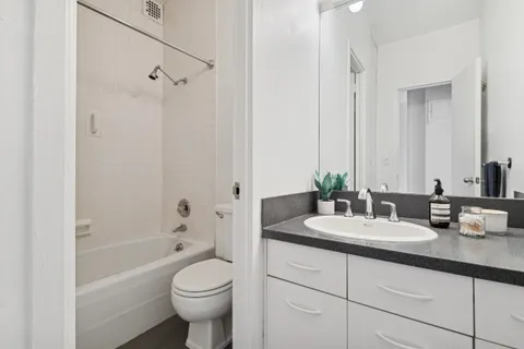 a bathroom with a granite countertop sink toilet and shower
