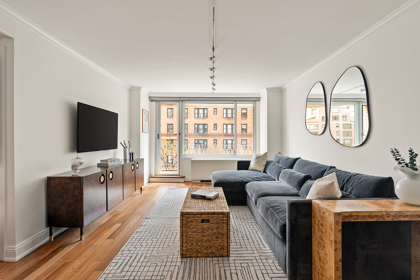 a living room with furniture a flat screen tv and a floor to ceiling window