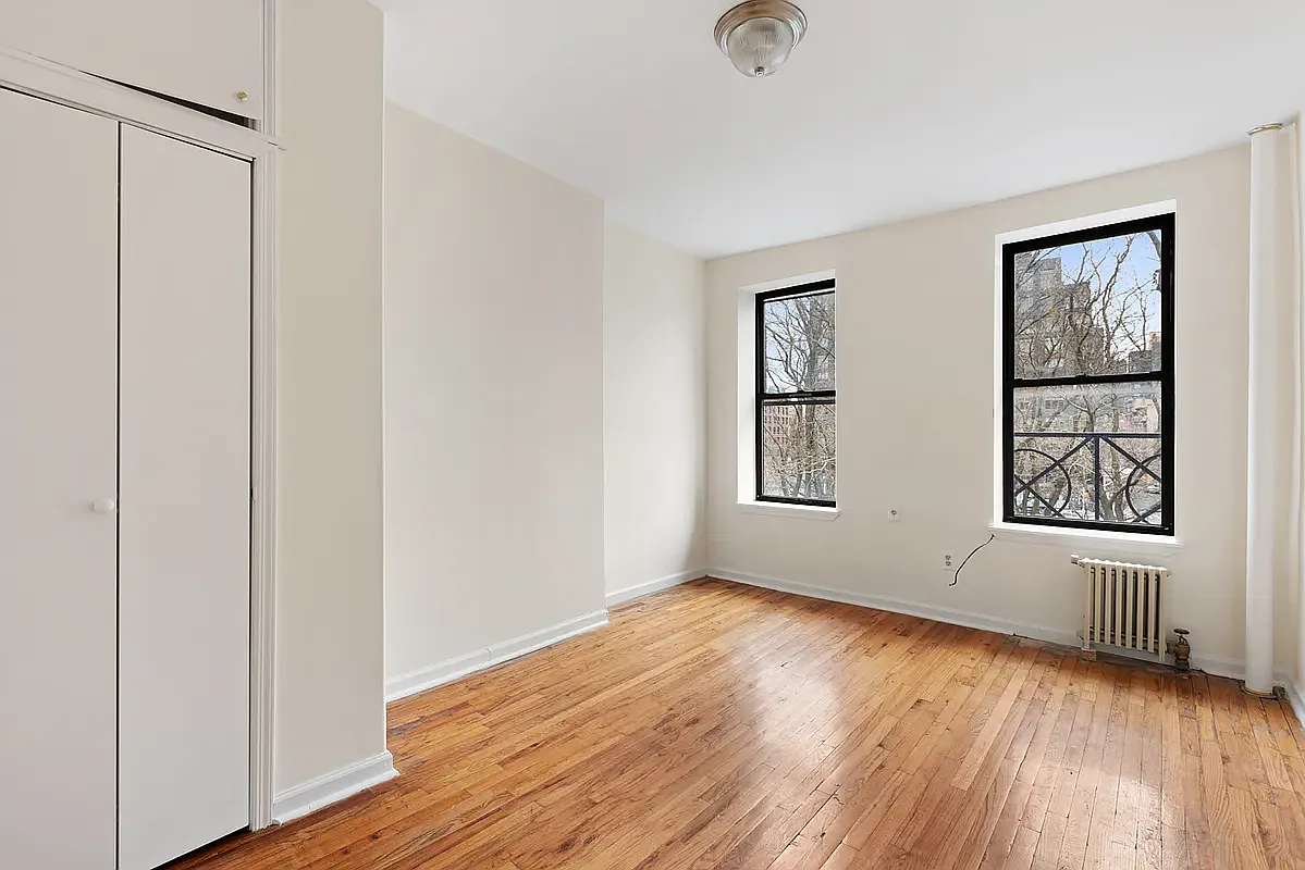 an empty room with wooden floor cabinet and windows