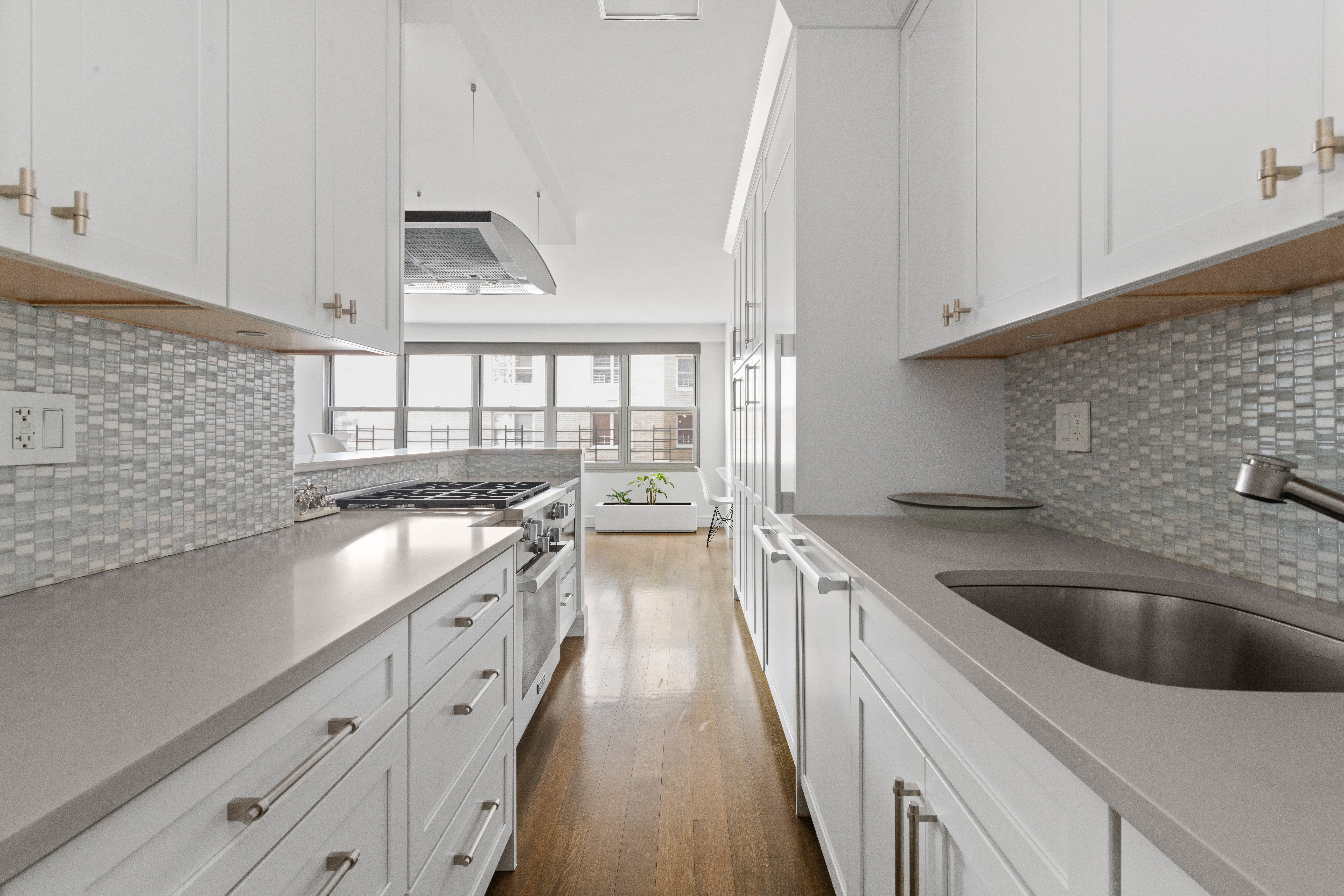 363 East 76th Street, Unit 7C Manhattan, NY 10021 - Photo 4 of 19 a kitchen with granite countertop a sink dishwasher a stove and white cabinets with wooden floor