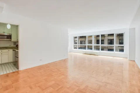 a view of an empty room with a window and kitchen area