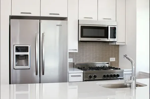 a kitchen with stainless steel appliances granite countertop a stove and a refrigerator with white cabinets