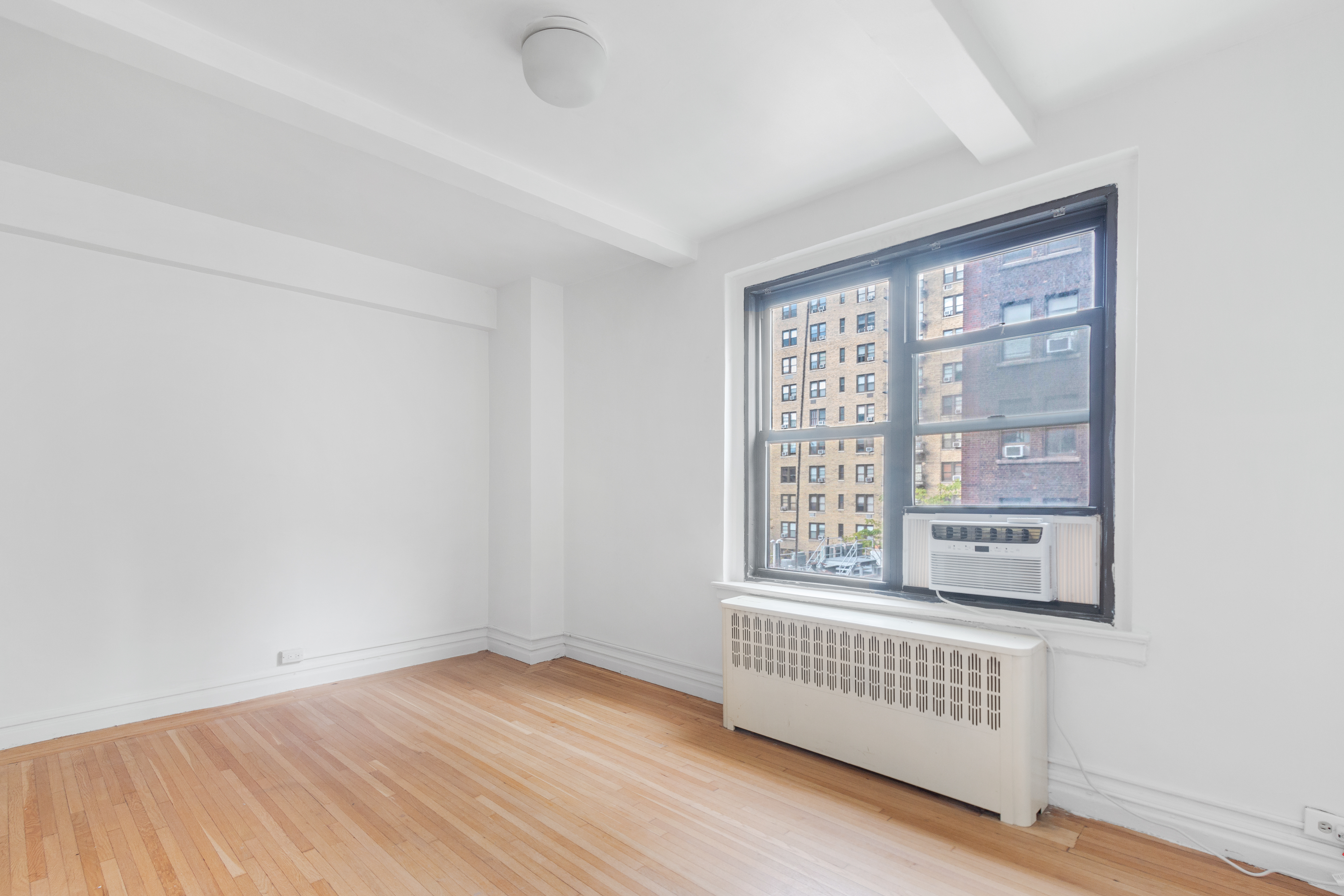 235 West End Avenue, Unit 8G Manhattan, NY 10023 - Photo 4 of 13 a view of an empty room with wooden floor and a window