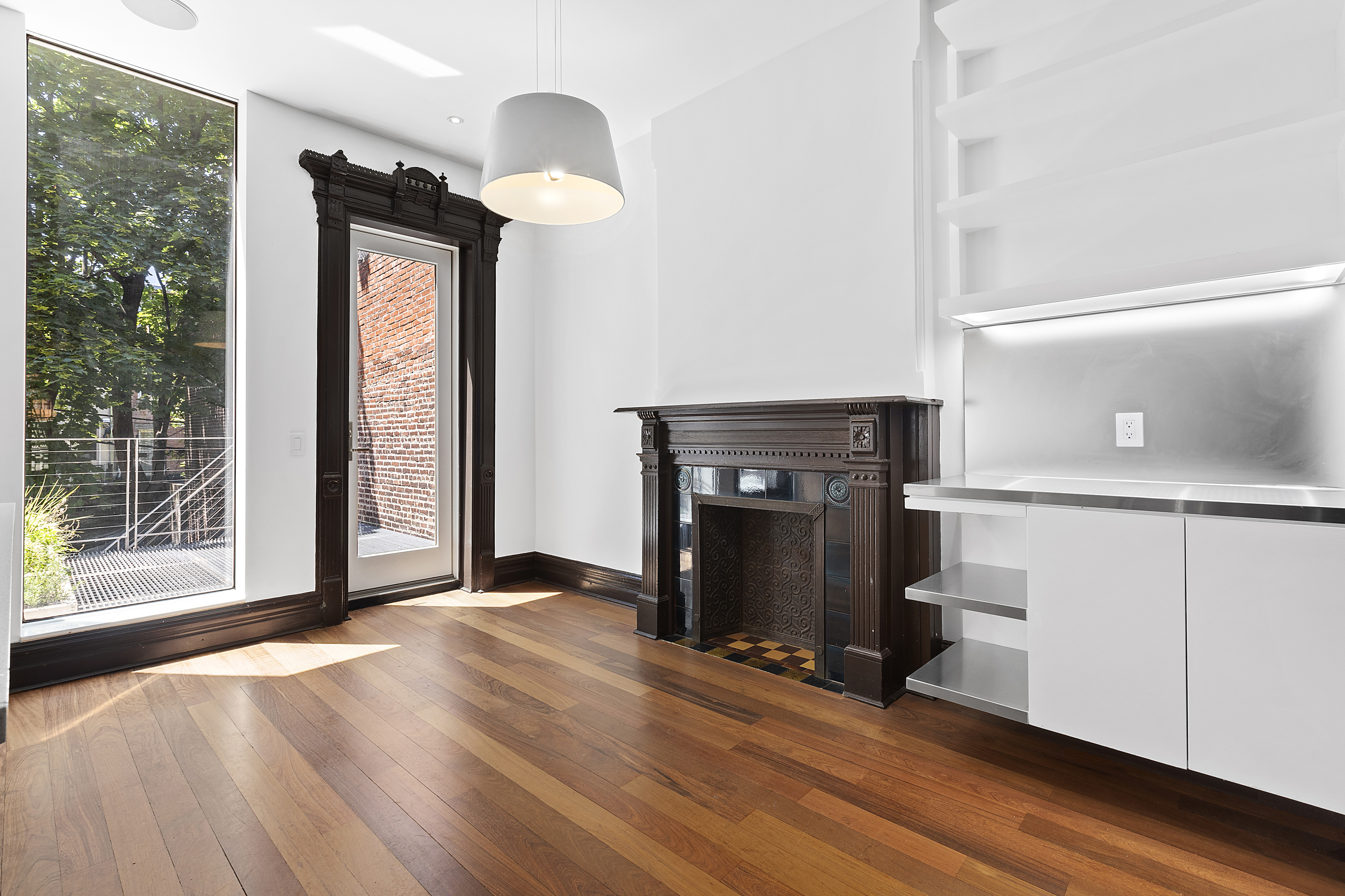 64 Clifton Place Brooklyn, NY 11238 - Photo 6 of 22 a view of an empty room with wooden floor a fireplace and a window
