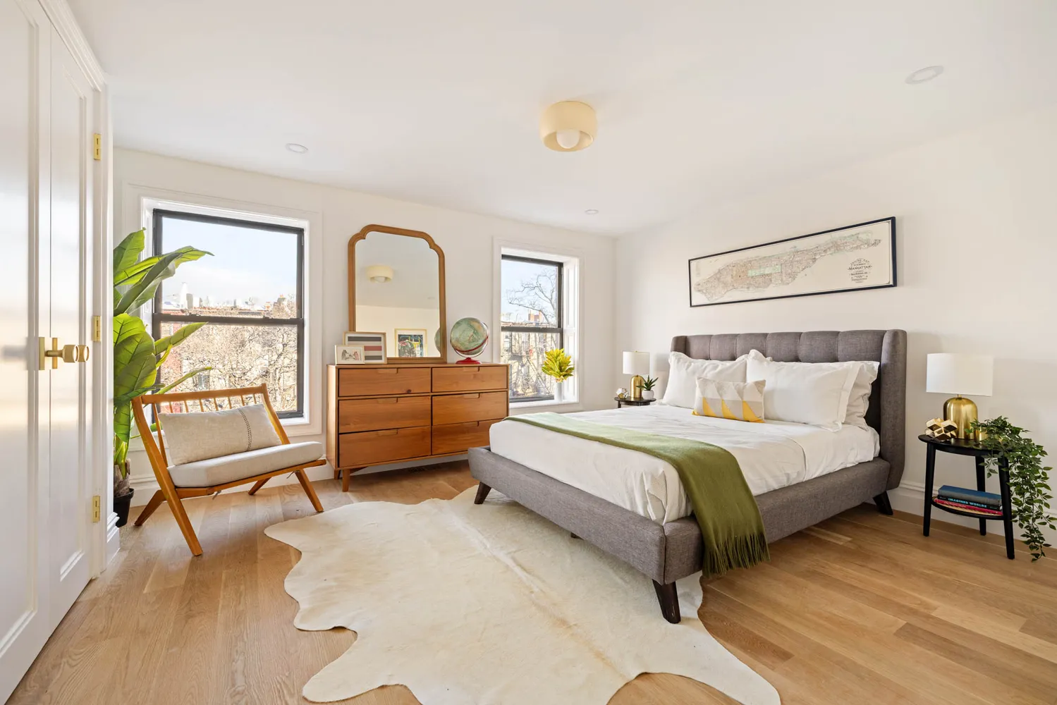 a spacious bedroom with a bed a dresser and a large window