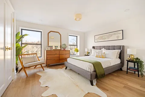 a spacious bedroom with a bed a dresser and a large window