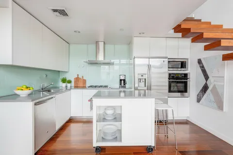 a kitchen with stainless steel appliances a sink a stove a refrigerator cabinets and wooden floor