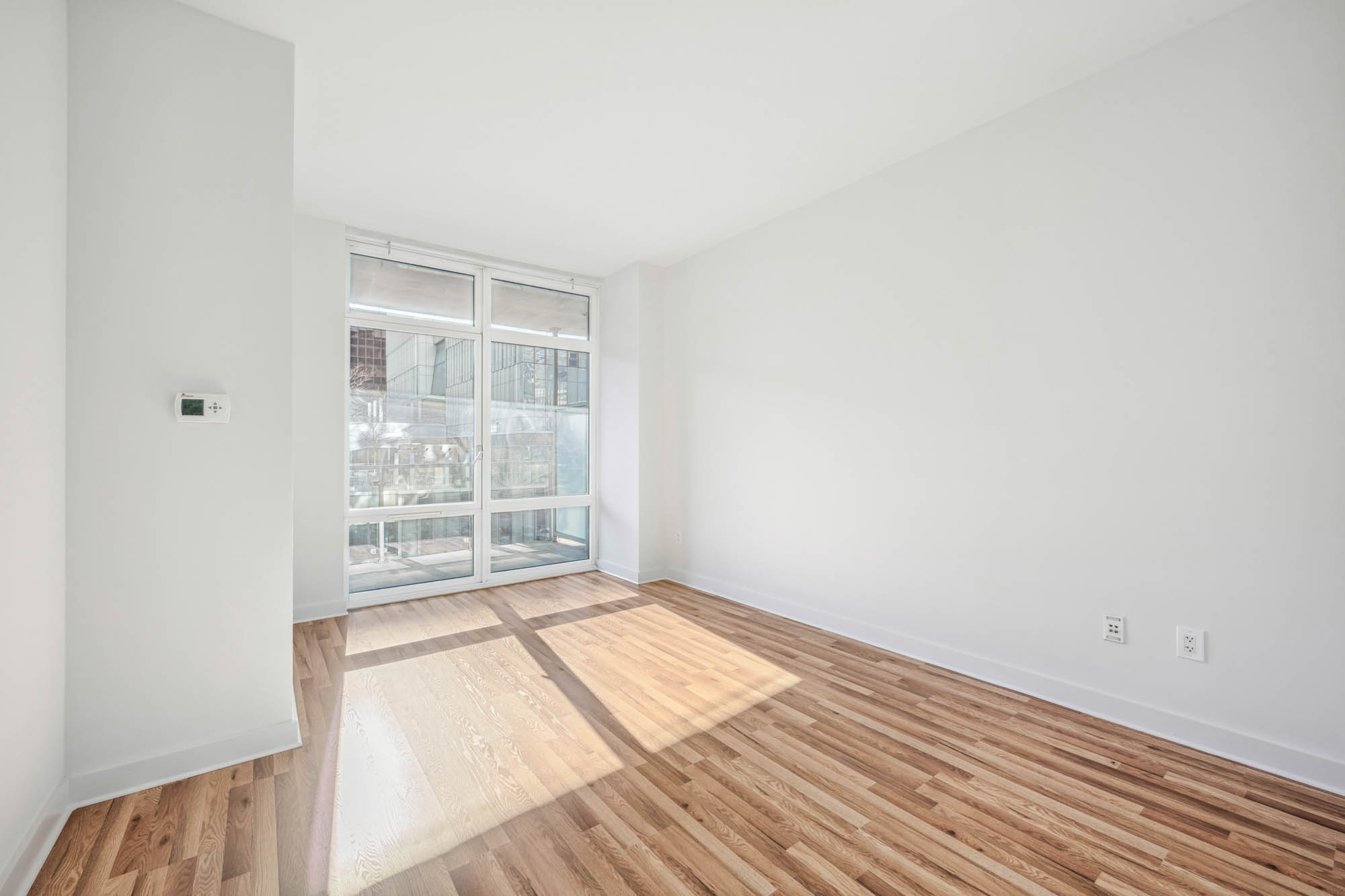 555 West 59th Street, Unit 7E Manhattan, NY 10019 - Photo 5 of 9 a view of an empty room with wooden floor and a window