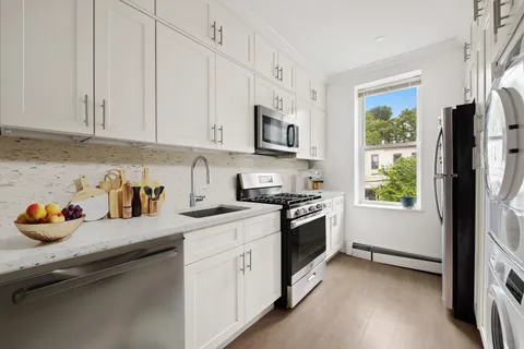 a kitchen with stainless steel appliances granite countertop a stove a sink dishwasher and a refrigerator with wooden floors