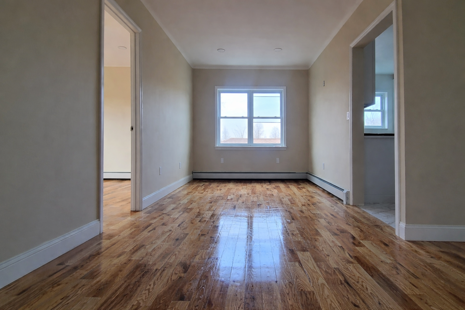 97-08 Plattwood Avenue, Unit 2 Queens, NY 11417 - Photo 4 of 10 an empty room with wooden floor and windows