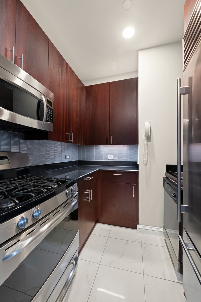1 Central Park West, Unit 1506 Manhattan, NY 10023 - Photo 5 of 16 a kitchen with stainless steel appliances granite countertop a stove and a microwave