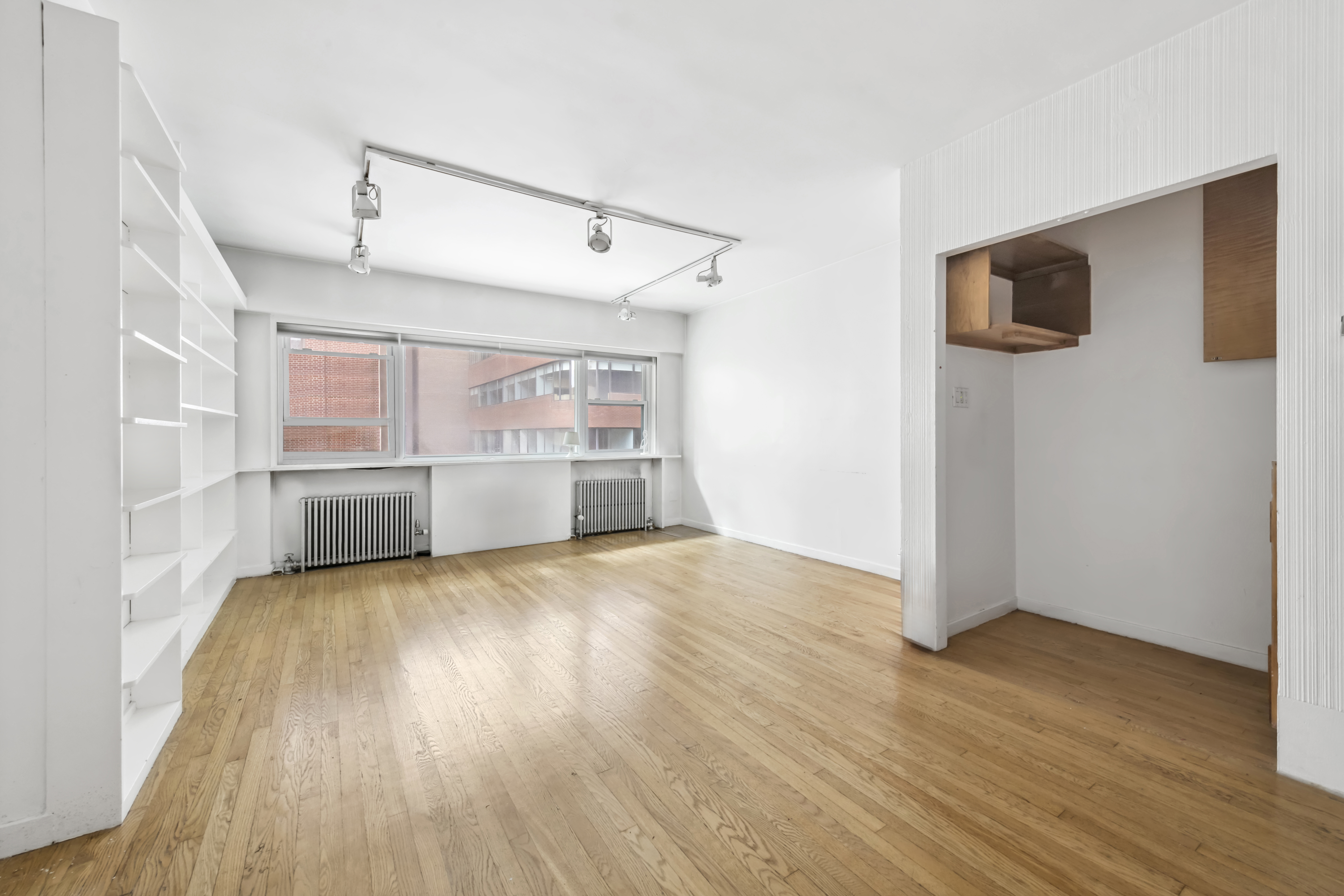 209 East 48th Street Manhattan, NY 10017 - Photo 7 of 13 an empty room with wooden floor and windows