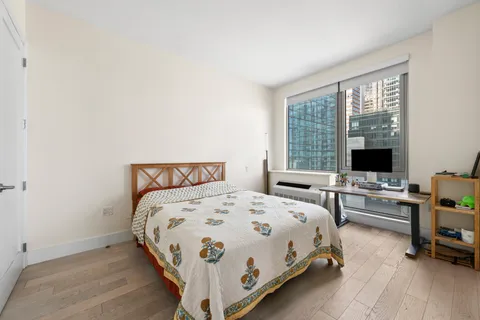 a large bed sitting in a bedroom next to a window with bookshelf