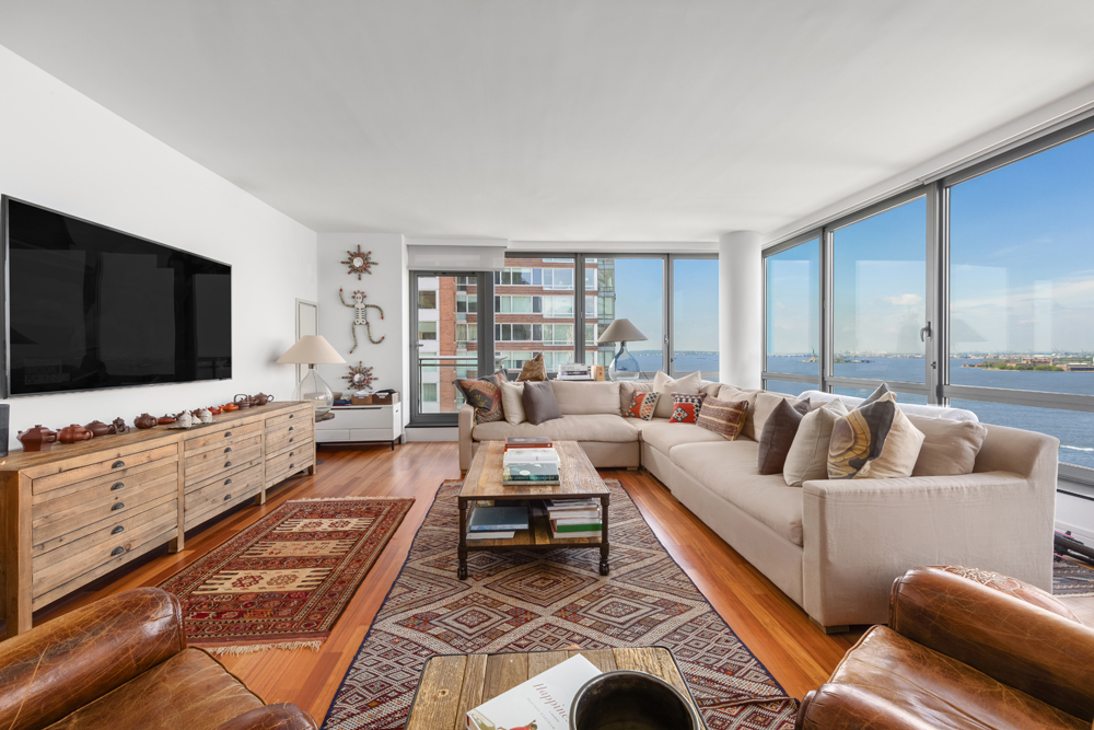 30 West Street, Unit 19F Manhattan, NY 10004 - Photo 2 of 12 a living room with furniture and a flat screen tv