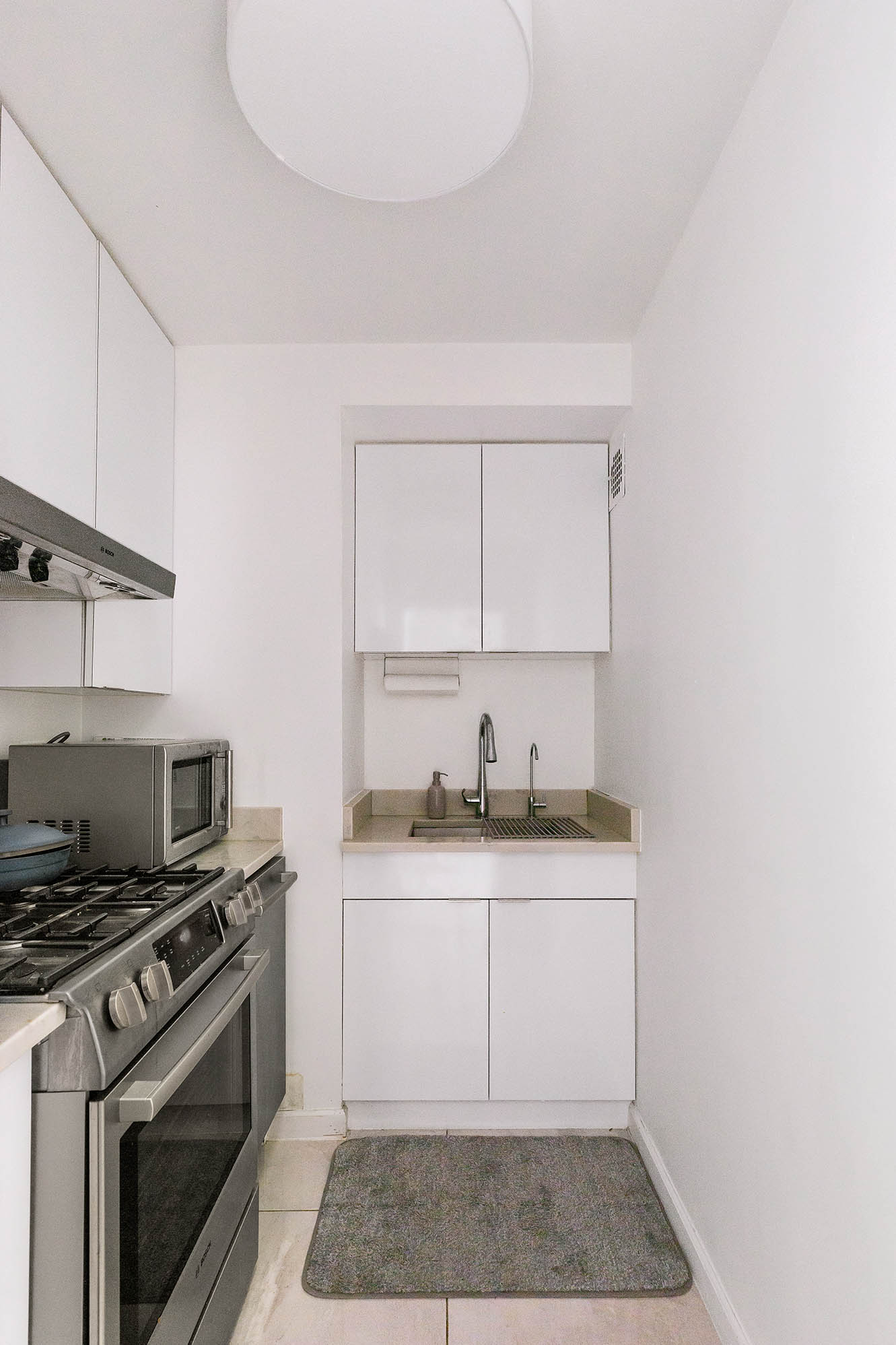 135 East 54th Street, Unit 6M Manhattan, NY 10022 - Photo 5 of 10 a white kitchen with granite countertop a stove top oven