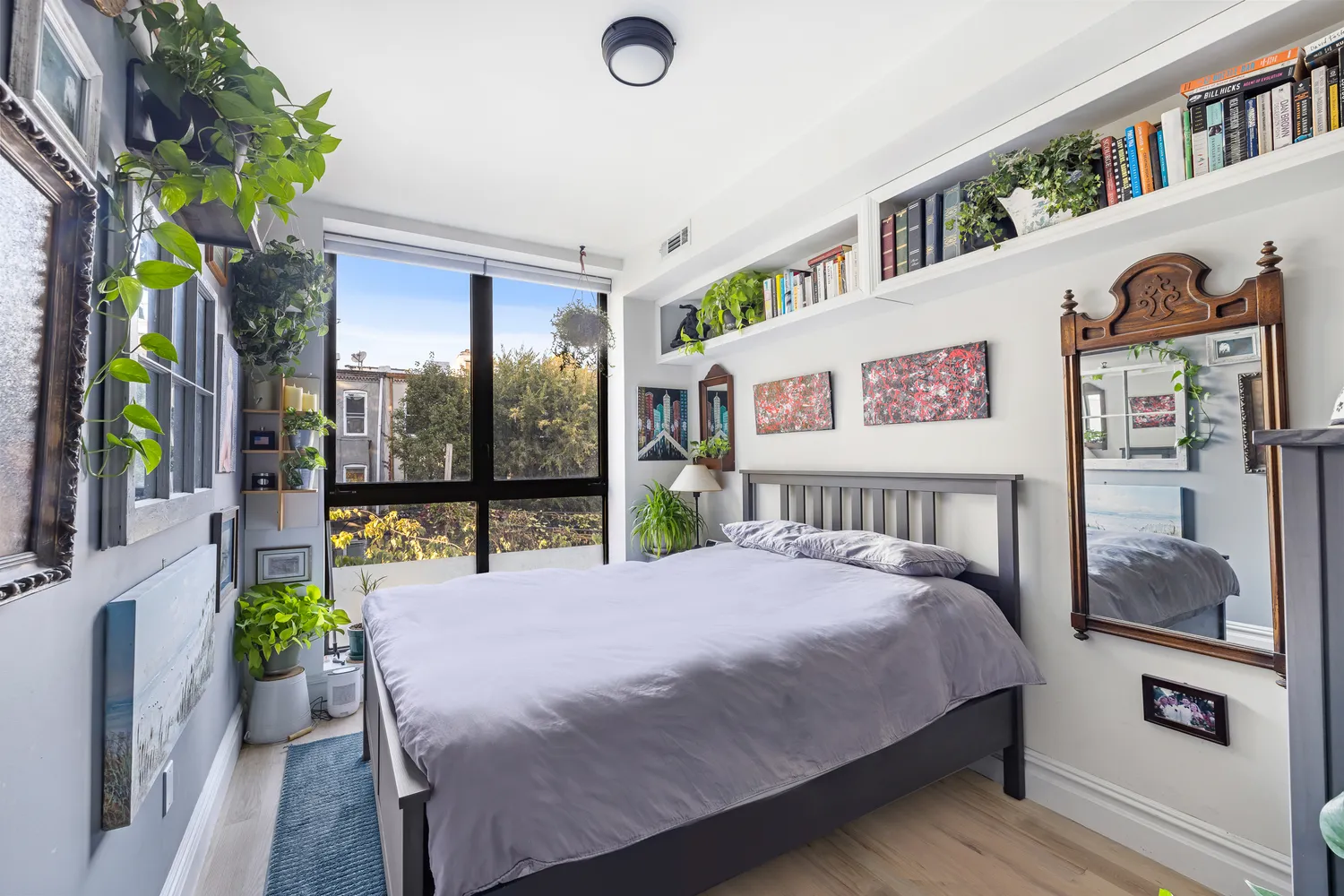a bedroom with a bed bookshelf and a large window