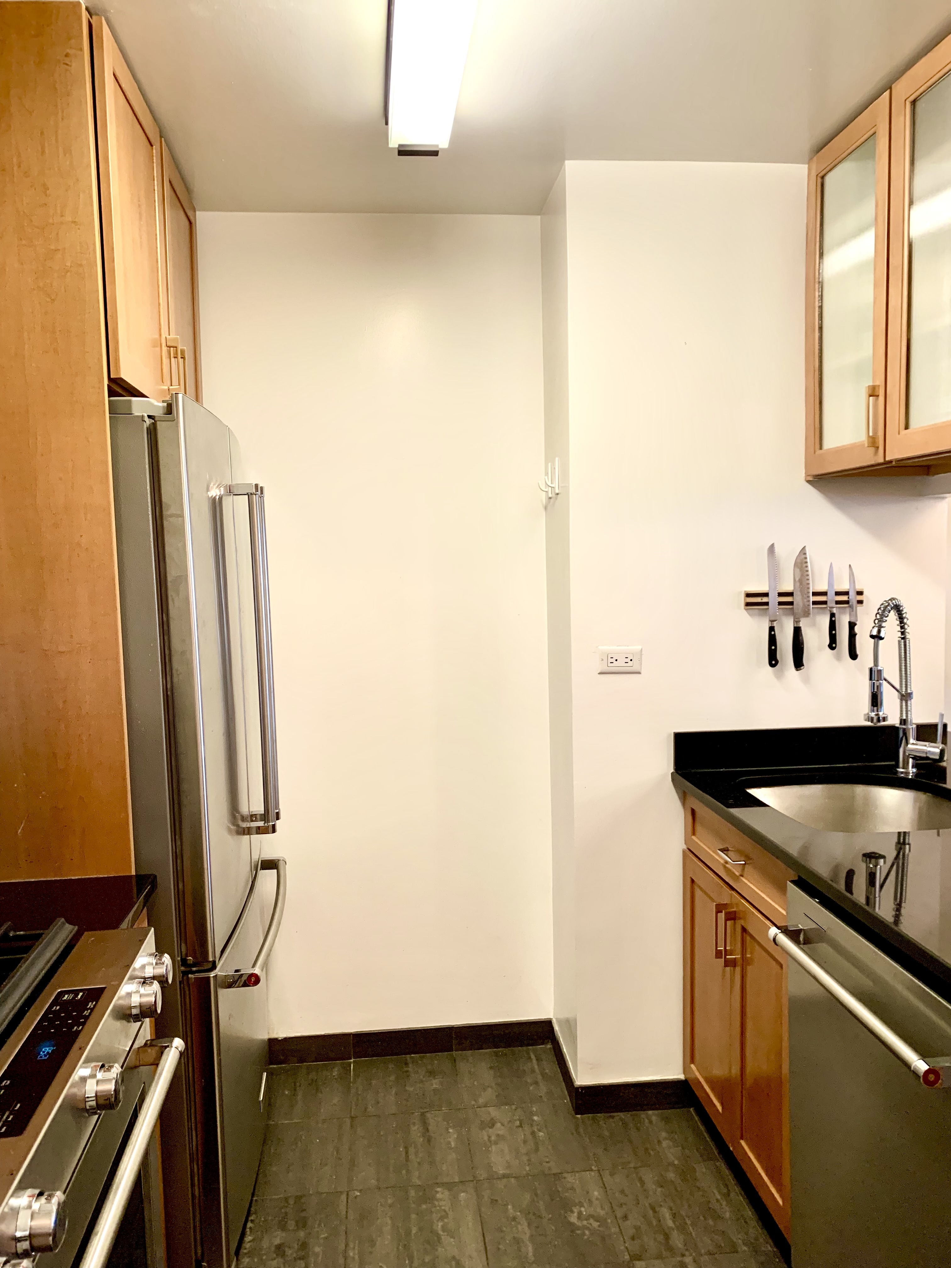 200 Rector Place, Unit 2C Manhattan, NY 10280 - Photo 6 of 19 a kitchen with wooden floor and cabinets
