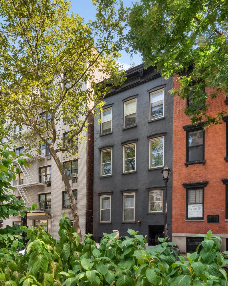 a view of a patio with couches and table and chairs under an umbrella with large trees