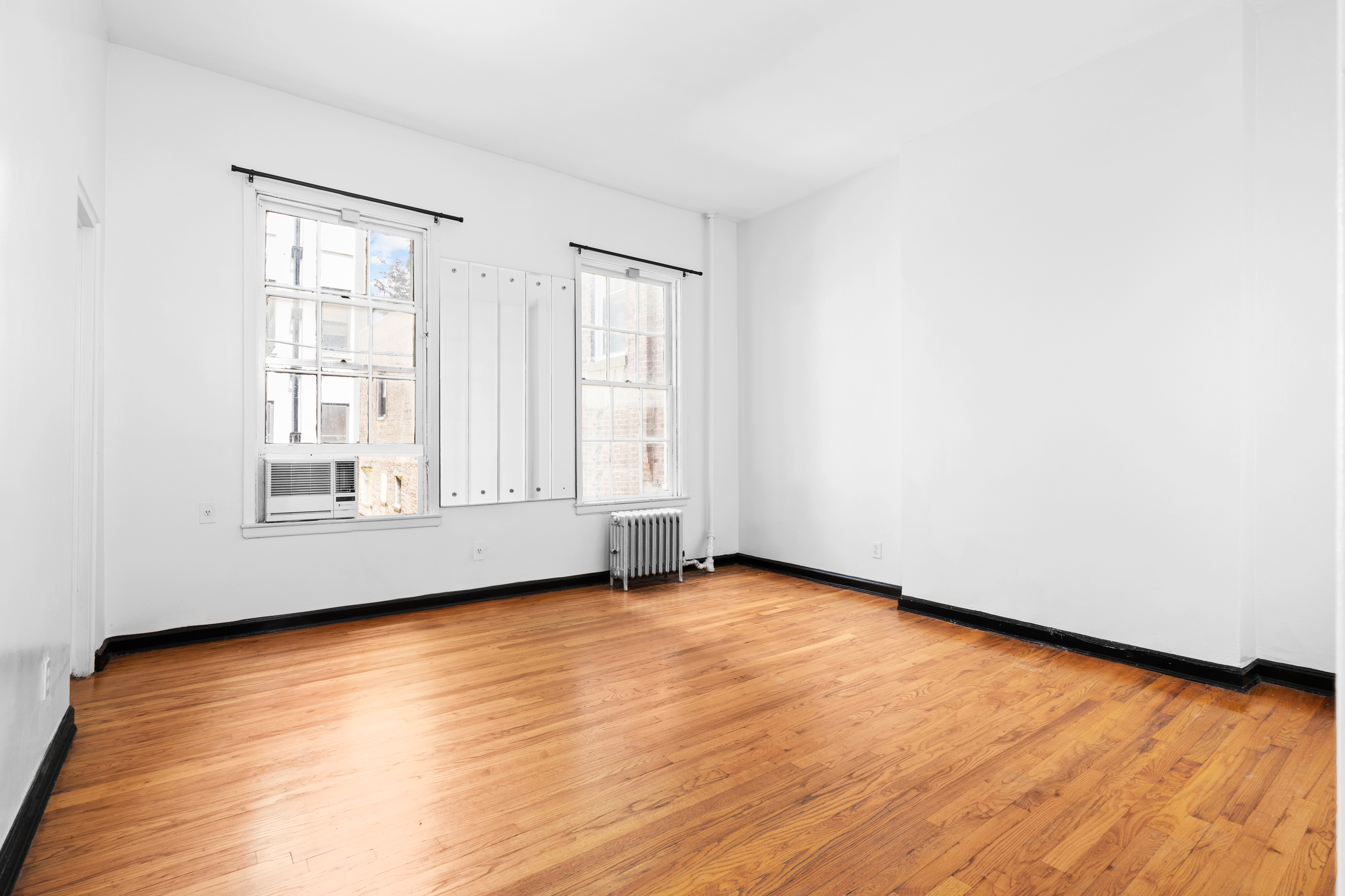305 East 12th Street, Unit PARLOR Manhattan, NY 10003 - Photo 3 of 5 an empty room with wooden floor and windows